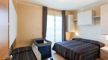 Zimmer mit Kinderbett und Bett für zwei Kinder