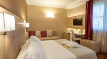 Camera matrimoniale con divano, tv e scrivania