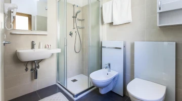Privates Badezimmer mit wandmontiertem Haartrockner und Duschkabine