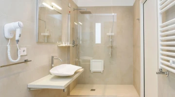Salle de bain privative avec cabine de douche et sèche-cheveux mural