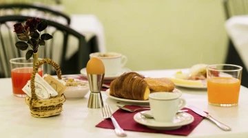Breakfast with croissants, eggs, cappuccino and fruit juice