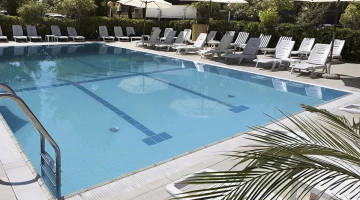 Piscine avec espace solarium dans le jardin