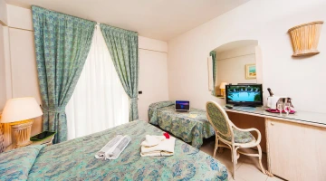 Dreibettzimmer mit TV und Schreibtisch