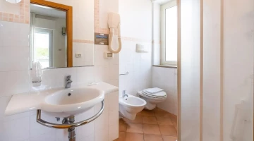 Privates Badezimmer mit wandmontiertem Haartrockner und Duschkabine