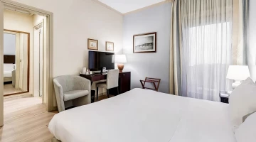 Chambre avec TV, fauteuils et balcon