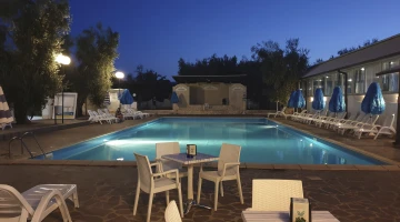 Night view of the swimming pool with tables and chairs
