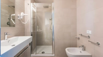 Salle de bain avec cabine de douche et sèche-cheveux