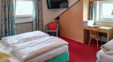 Dreibettzimmer mit TV und Schreibtisch