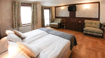 Double bedroom with TV and armchairs