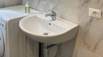 Détail de la salle de bain avec lavabo et machine à laver