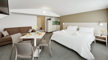 Sistemazione con divano, letto matrimoniale e angolo cottura