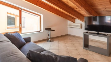 Wohnzimmer im Dachgeschoss mit Fernseher und Sofa