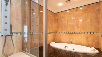 Salle de bains avec baignoire balnéo et douche