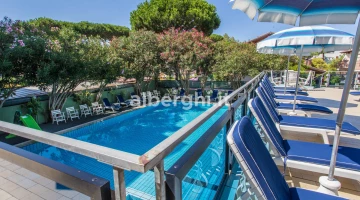 Vue sur la piscine depuis la terrasse avec parasols et transats